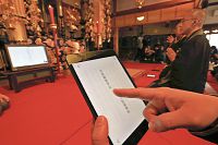 神居文彰住職の読経にあわせて文字をたどる参加者ら=宇治市の平等院